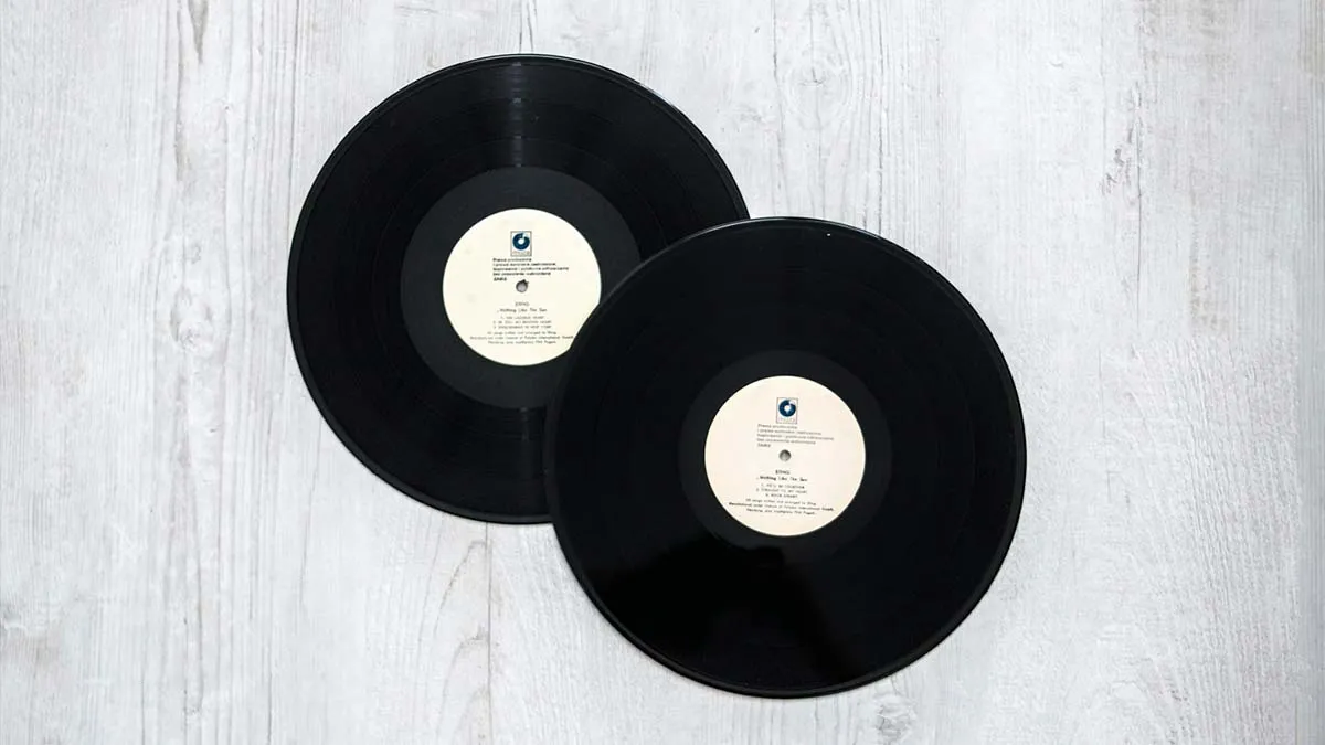 Vintage black vinyl records on a light wooden surface, ideal for music collectibles and retro music themes.