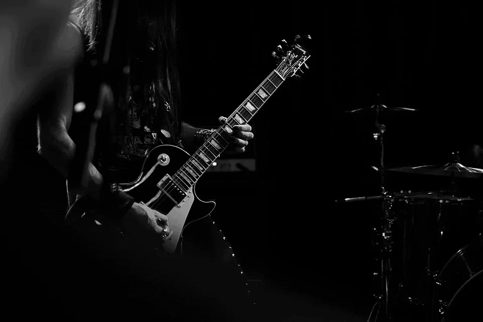 Electric guitar player performing on stage at a music venue in black and white; music industry, live performance, musician, c
