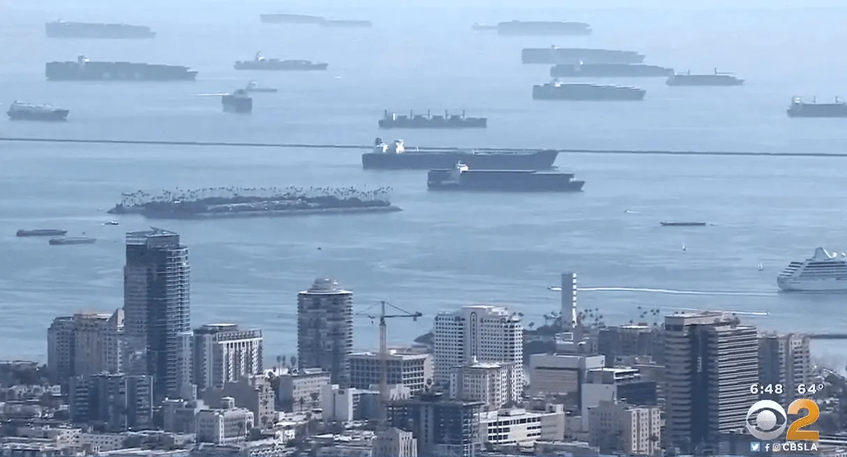 Cargo ships docked in a busy harbor with high-rise buildings in the foreground, illustrating maritime industry and urban skyl