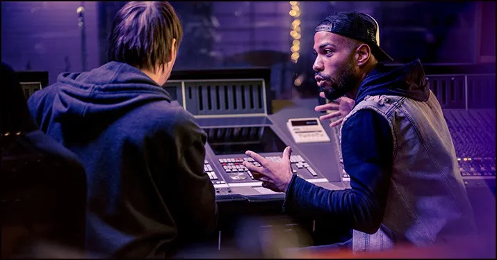 Recording studio session with two music producers collaborating on a track, using professional audio equipment and mixing con