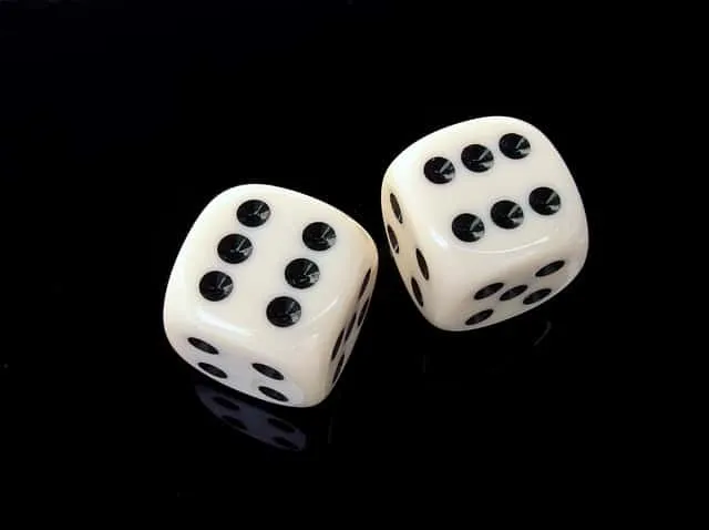 Two white dice with black dots showing the numbers 4 and 6 on a black background, used to symbolize chance, luck, or gaming.