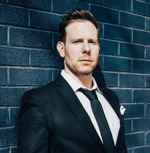 Business professional in a suit standing against a dark blue brick wall, emphasizing music industry insights, digital marketi