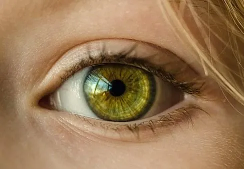 Vivid green eye with detailed iris close-up, natural eyelashes, and subtle skin tones showcasing clarity and beauty.