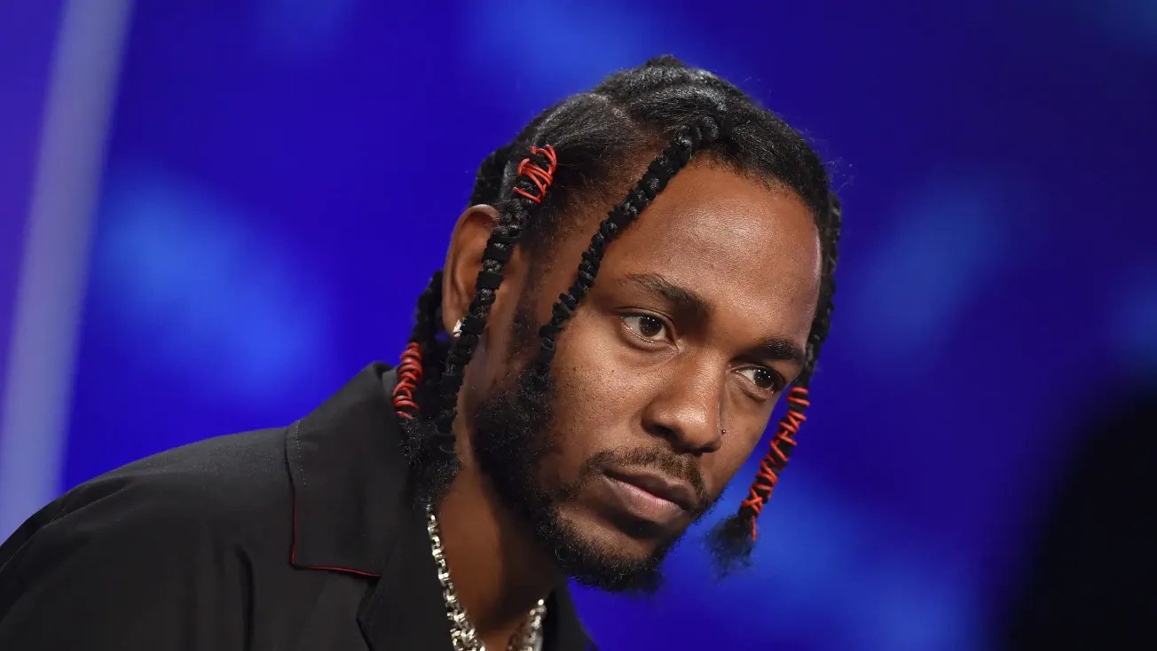 Vibrant close-up of a Black male artist with styled braided hair featuring red accents, on stage during a music event, highli