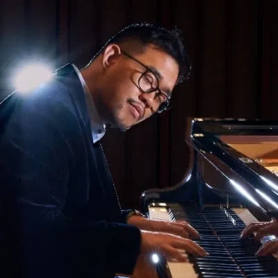 A professional musician playing piano in a dimly lit studio or concert hall at night, emphasizing musical creativity and tale