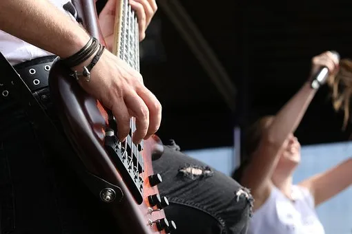 Guitarist playing electric guitar at live concert, focus on hand and instrument, music performance, rock band, stage lighting