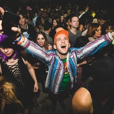 Colorful party scene with excited young people enjoying music at a nightclub or music event.
