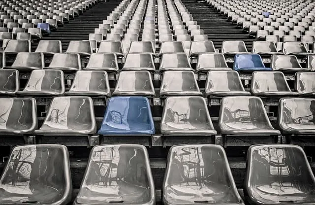 Empty stadium seats with a mix of black and blue chairs, reflecting in the glossy surfaces, illustrating waiting or anticipat