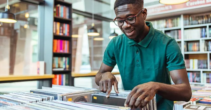 Record store with a person browsing vinyl records in a bright, modern music shop, showcasing a love for music, vinyl collecti