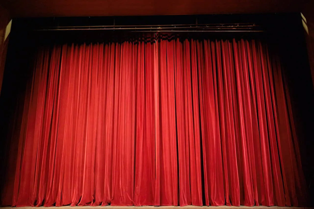 Red theater stage curtain with theater rigging and stage trim.