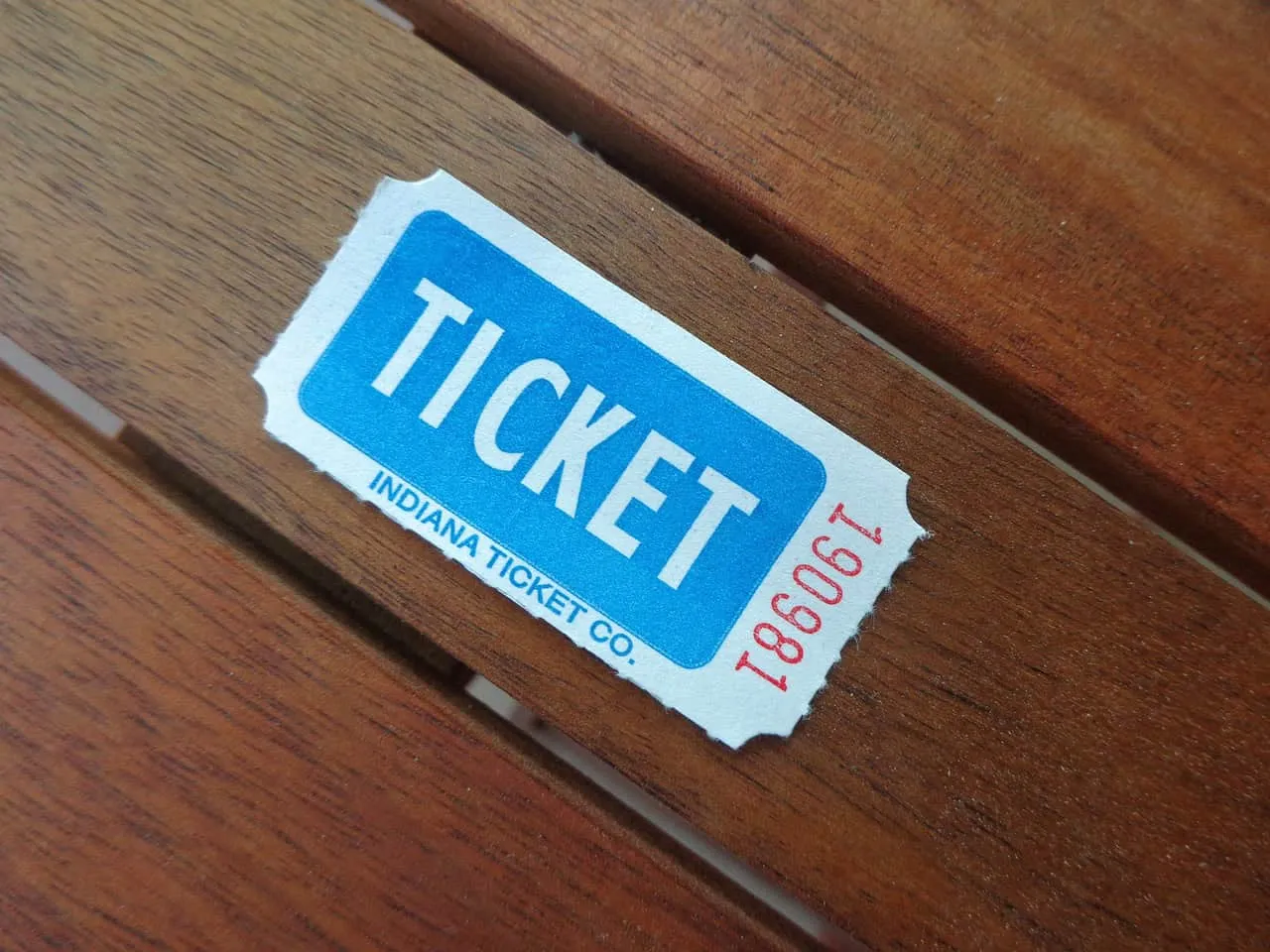Blue Indiana ticket stub on wooden surface, event admission ticket, public transportation or concert ticket, vintage ticket d