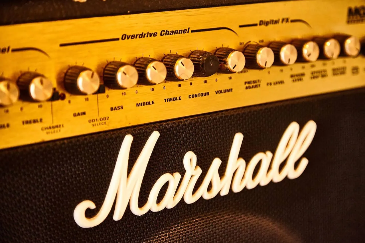 Marshall amplifier with sound control knobs and gold-colored audio equipment in close-up shot, emphasizing music production a