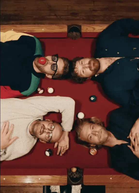 Nostalgic group of friends lying on a billiards table playing pool and having fun, relaxed social gathering, casual entertain