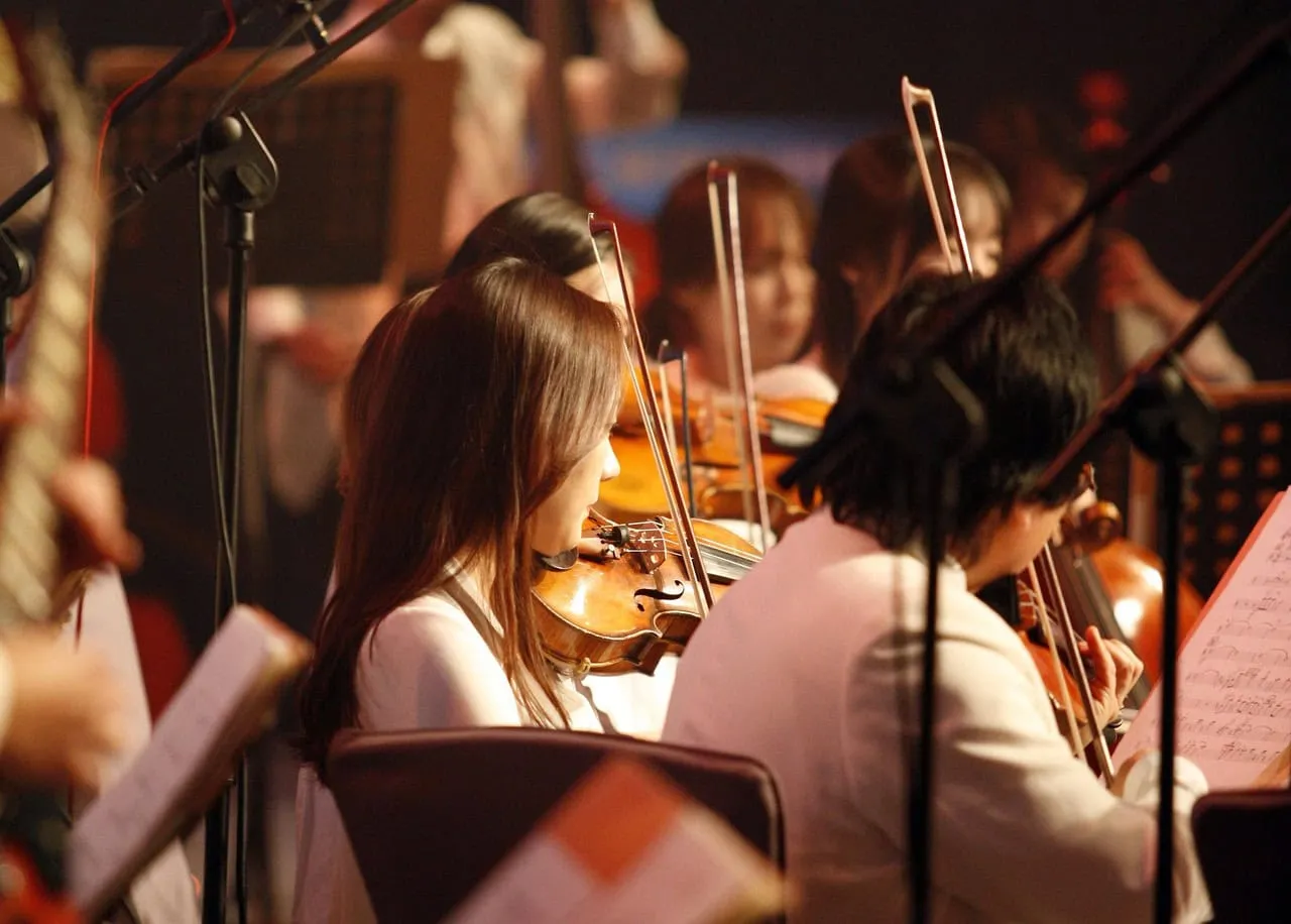 Young orchestral musicians playing violins during a rehearsal or performance.