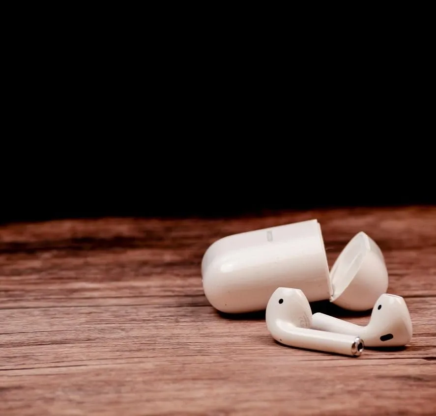 Wireless earbuds with charging case on wooden surface, technology and music accessories, portable audio device, modern earbud