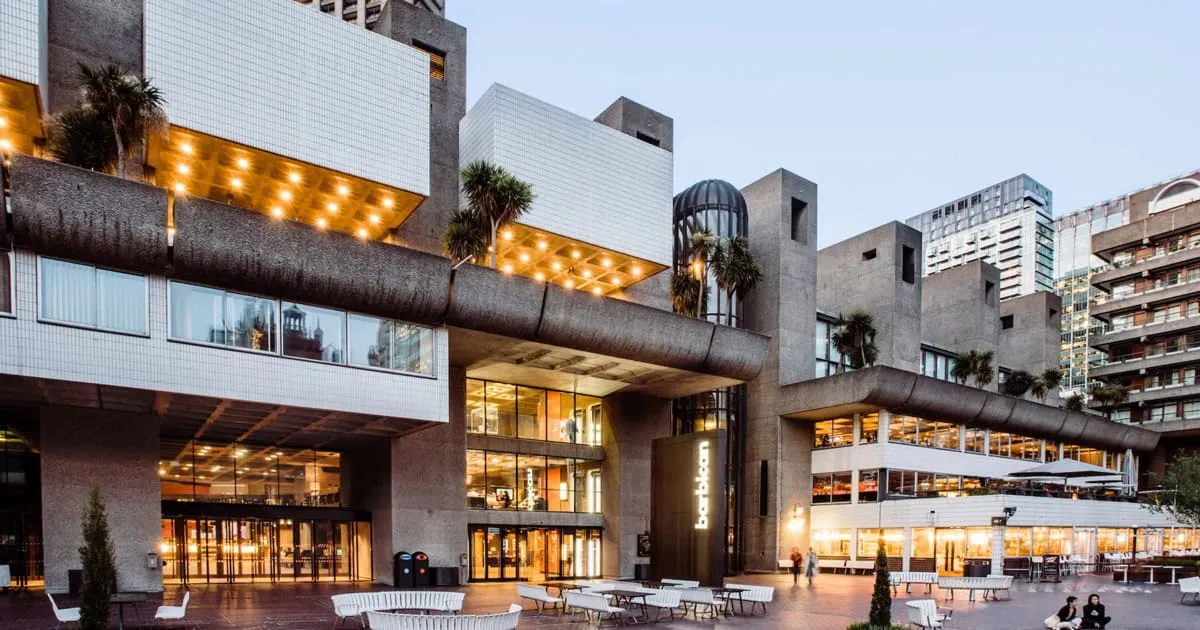 Modern urban building with glass windows, outdoor seating, and warm lighting, highlighting architecture and cityscape, perfec