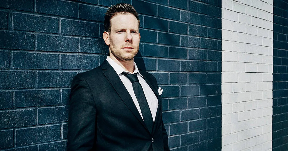 Professional businessman in a tailored suit standing against a modern brick wall, representing insights on the music industry