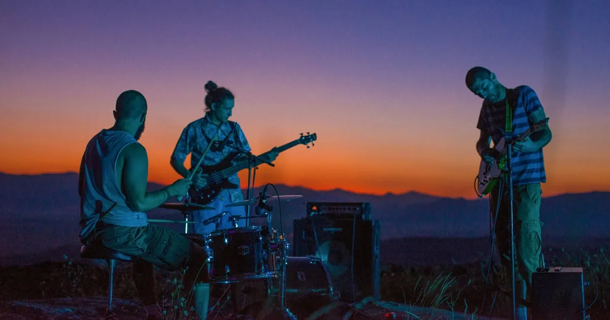 A band performing live at sunset outdoors, showcasing music, musicians, instruments, guitar, bass, drums, sunset scenery, and
