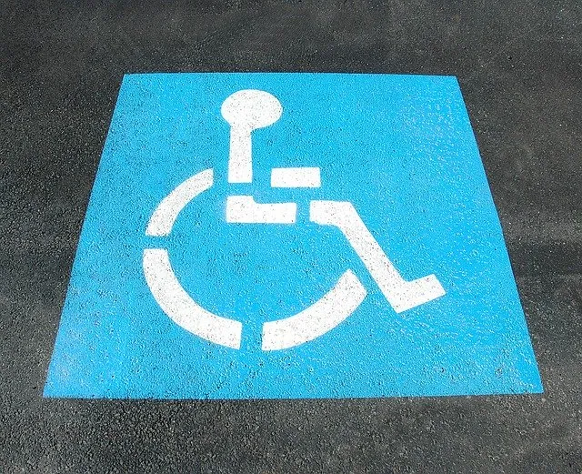 Wheelchair accessible parking space painted in blue and white symbols on asphalt, indicating disability access.
