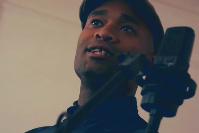 Man recording music vocals with microphone in professional studio, singing passionately, music production, sound engineering,