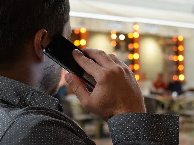 Man talking on mobile phone in a busy indoor setting with blurred background elements.