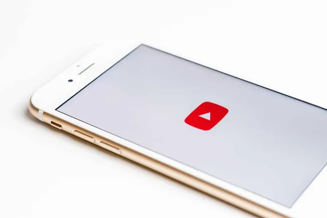 Mobile phone displaying the YouTube app icon on a clean white background.