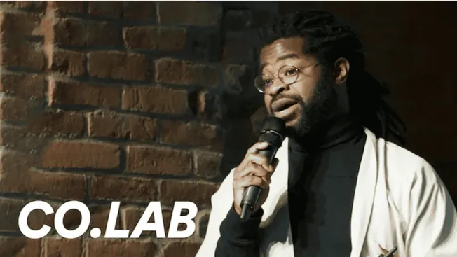 Creative Black Man Giving Live Speech with Microphone at Comedy or Artistic Event, Brick Wall Background, Enthusiastic Expres