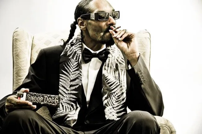 Luxury music executive wearing virtual reality glasses, smoking, holding a remote control, dressed in a tuxedo with a pattern