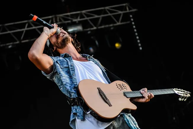 Vocalist with guitar performing live on stage at a music festival, emphasizing indie and rock music, concert performance, and