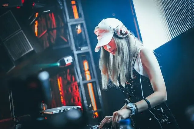 Female DJ wearing headphones at a music event, mixing tracks on DJ equipment in a nightclub setting, vibrant lighting and dig