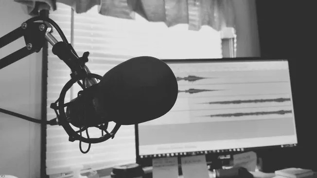 Microphone and recording setup in a podcast studio or radio station, with audio waveforms on a computer screen; Hypebot music