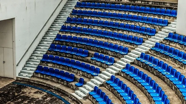 Empty blue stadium seats arranged in a curved pattern for sporting events or concerts, outdoor amphitheater seating with conc
