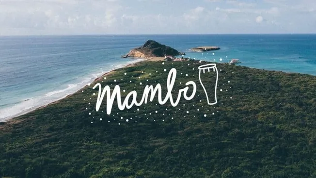 Mambo logo on coastal island aerial view of ocean shoreline and lush greenery with "mambo" handwritten text and beer glass ic
