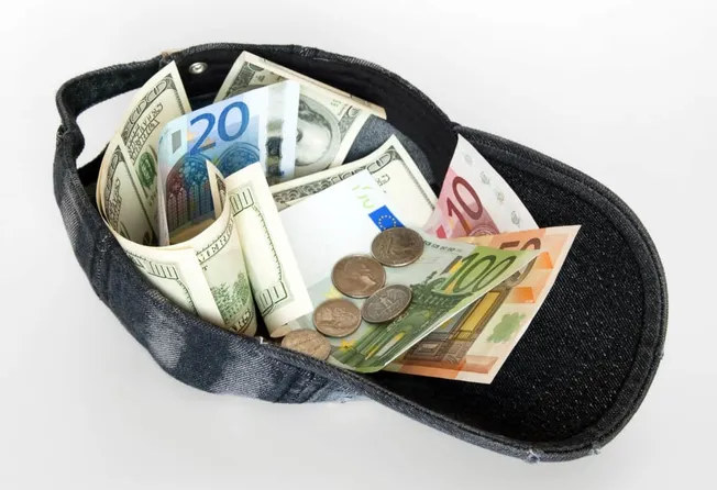 Rolled cash and euro coins in black coin pouch, financial savings and money management concept.
