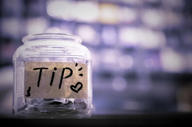 "Tip jar with handwritten notes, symbolizing advice or suggestions, on a blurred background highlighting tips, suggestions, a