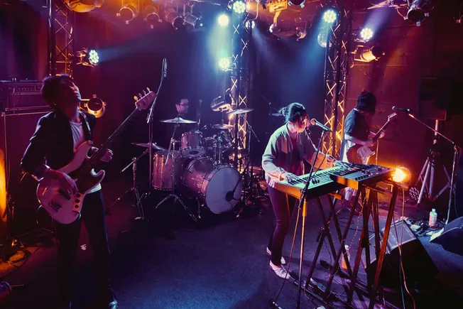Vibrant live band performance on stage with colorful lighting and musical instruments including guitars, drums, and keyboard