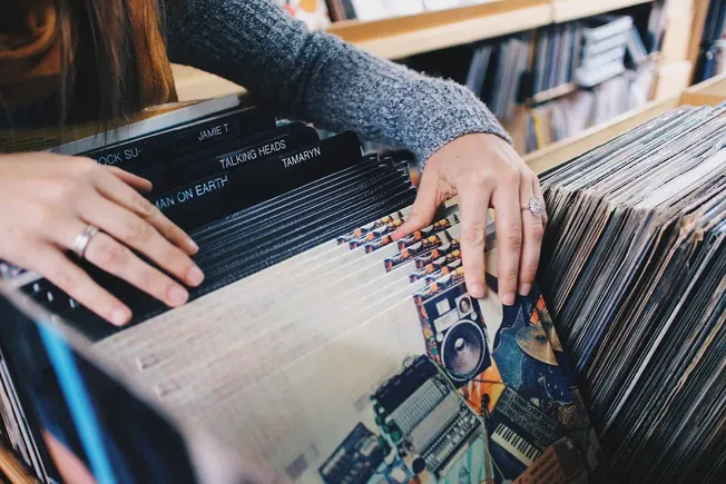 Vintage vinyl record collection organized in a wooden crate with record labels like "Talking Heads" and "Tame Impala" visible
