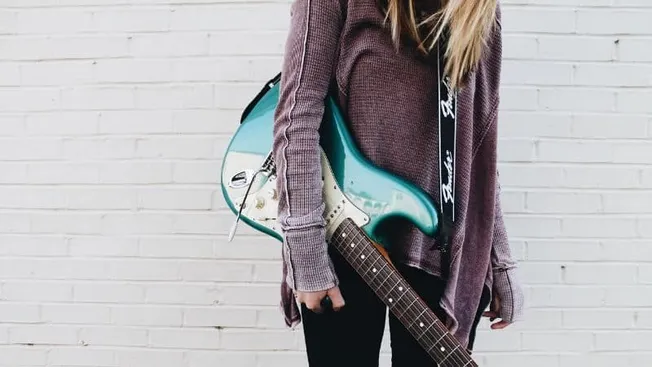 Electric guitar and backpack on a person against white brick wall, music, musician, alternative, indie, artist lifestyle, Hyp