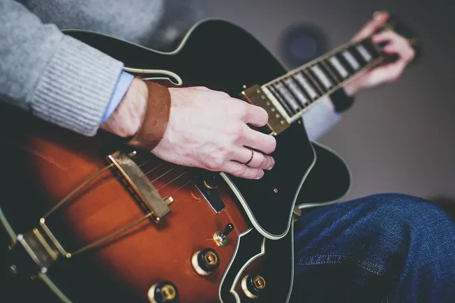Guitar player strumming an electric guitar, close-up shot showcasing hands and guitar details, music performance, musician pl