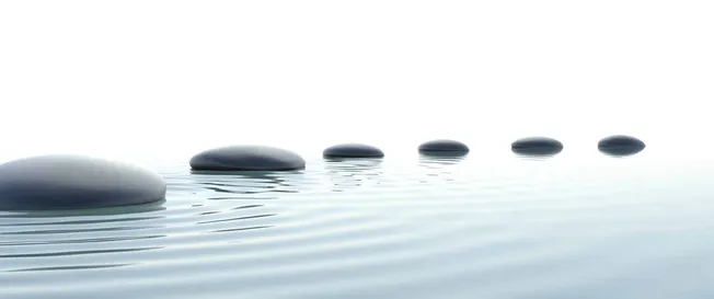 Smooth black stones floating on calm water with subtle ripples, minimalist zen landscape representing tranquility and balance