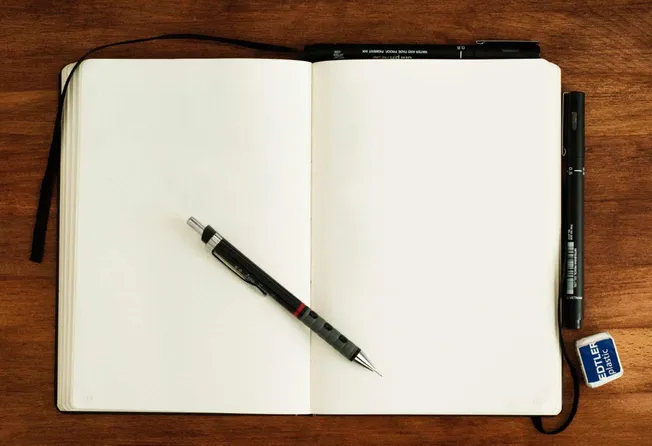 Open blank notebook with a black gel pen on wooden desk, featuring the Hypebot website context.