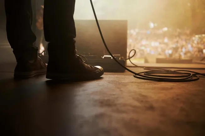 Studio musician performing live on stage with equipment in dim lighting, capturing a concert or music event for SEO-friendly