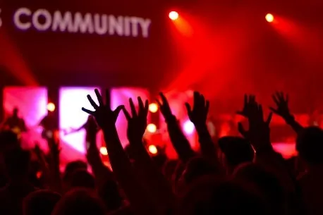 Dynamic concert crowd with raised hands at a live music event, emphasizing community engagement and music fans.