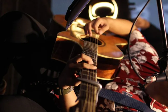Playing acoustic guitar during a live studio performance, highlighting music, musicianship, and entertainment.