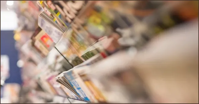Magazine rack with various magazines and newspapers at a bookstore or newsstand.