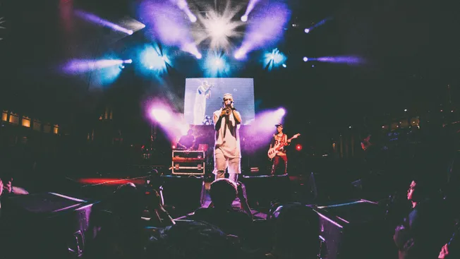 Concert performance at a live music event with stage lighting and band members playing guitars and singing on stage, showcasi