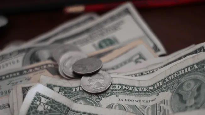 Stacks of US dollar bills and coins, representing earnings, revenue, or financial growth in the music industry and digital me