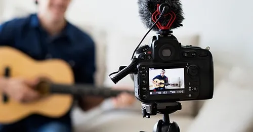 Professional musician filming a music video with guitar and camera setup for online content creation.