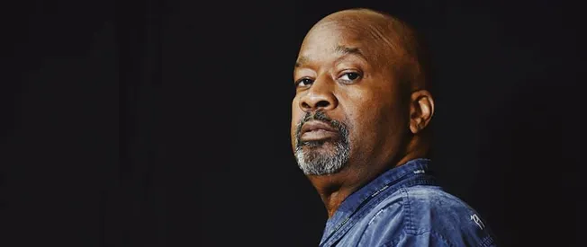 Powerful portrait of a confident African American man with a serious expression, wearing a denim jacket, against a dark backg