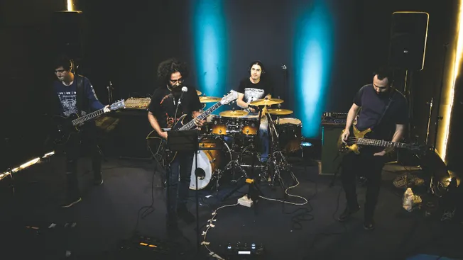 Guitar band performing live music on stage at Hypebot event with instruments and professional sound setup in dark concert ven